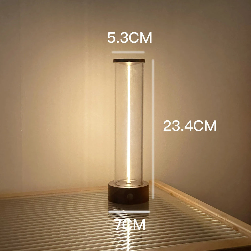 Glass cylindrical LED night light with magnetic base on a metal surface, showing USB charging port.