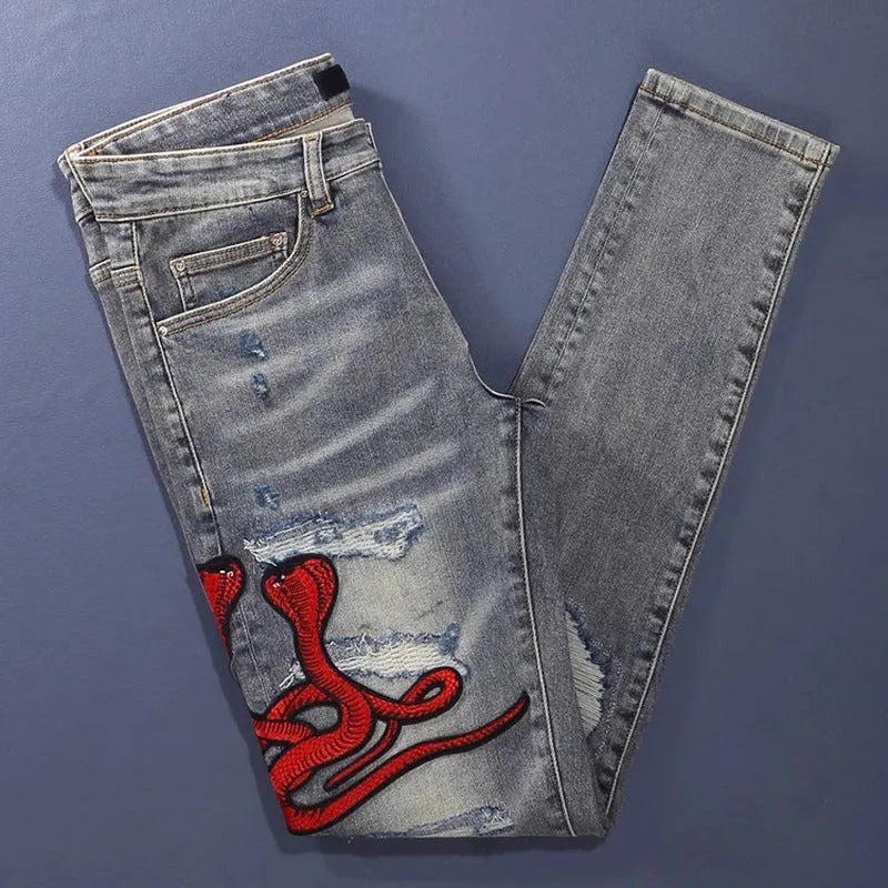 Slim fit jeans with a washed-out old colour finish, hole patches, and embroidery detail on the legs.