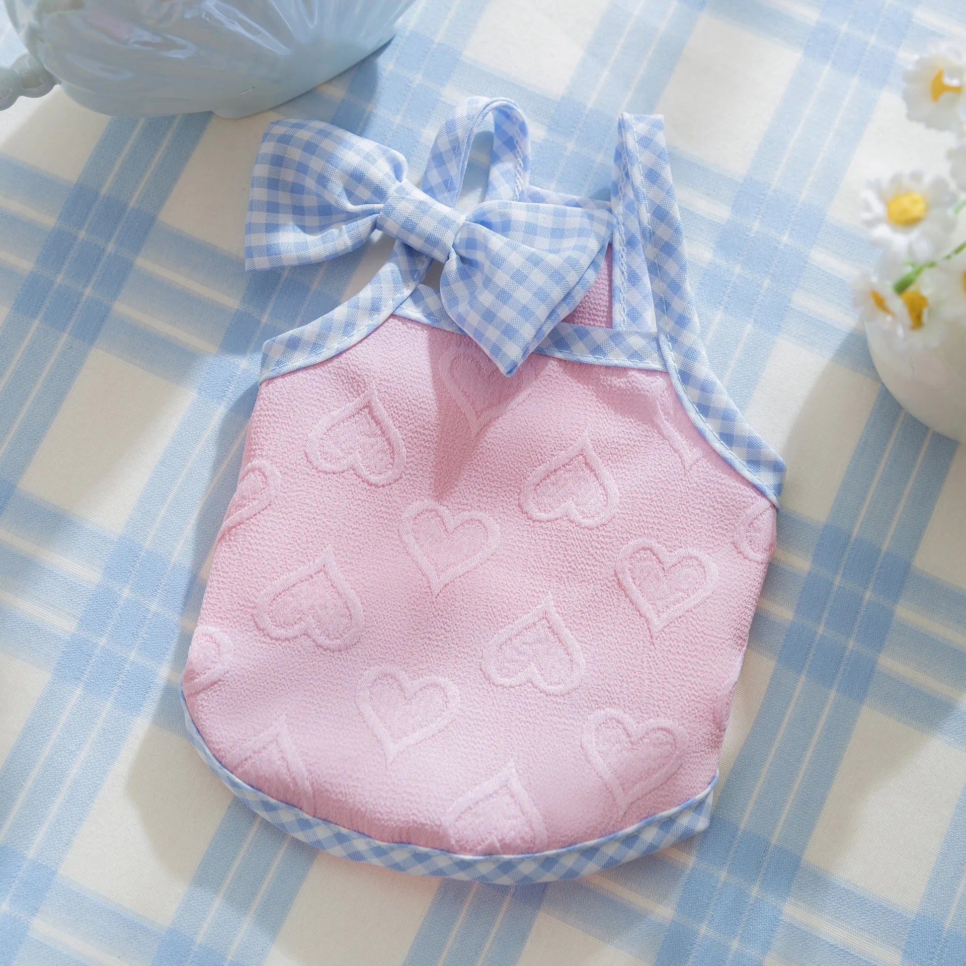 Small dog wearing heart pattern vest with bow suspenders in blue colour, showing elastic fit and decorative design