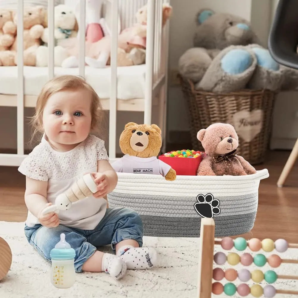 Small light beige handmade cotton rope storage basket with wooden handle on a table.