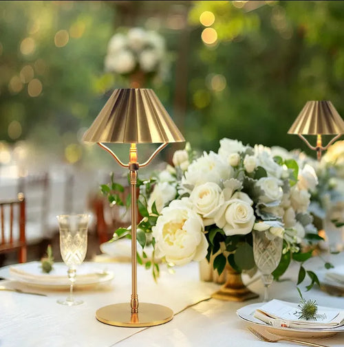 Gold alloy desk lamp with a fabric shade on a wooden table