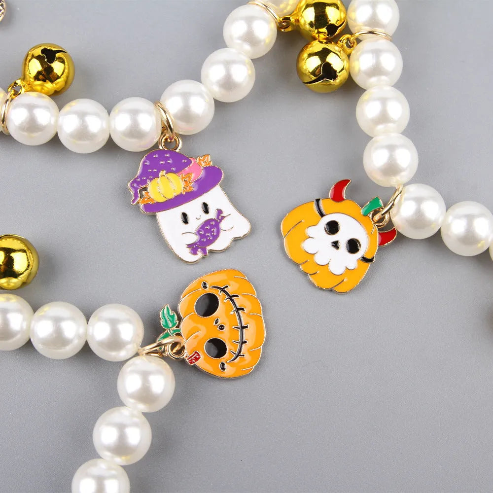 Adjustable simulated pearl necklace cat collar with a Halloween pumpkin charm in purple ghost, skull, or smile designs.