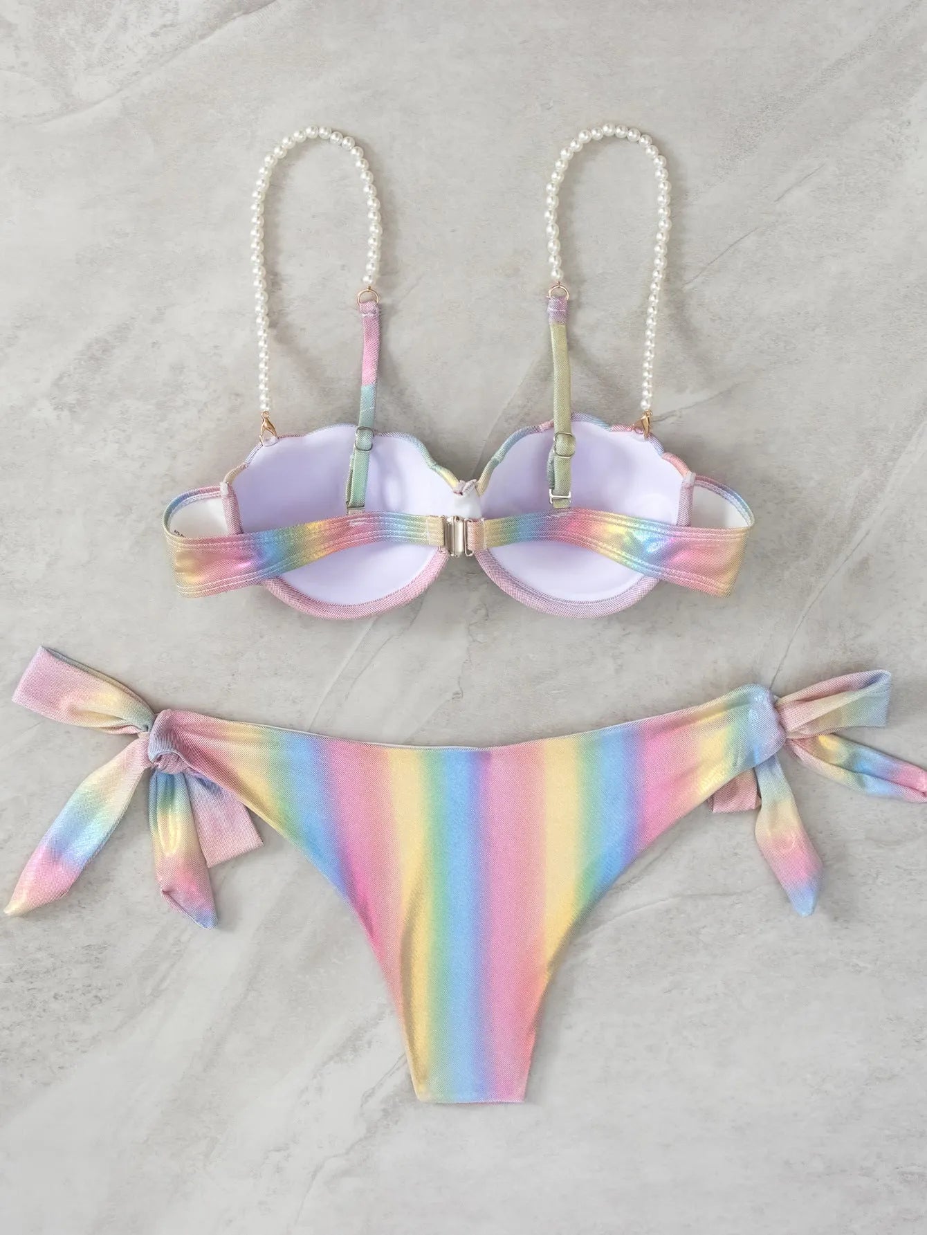 Women's shell rainbow patterned bikini swimsuit with a split tied front, on a mannequin.