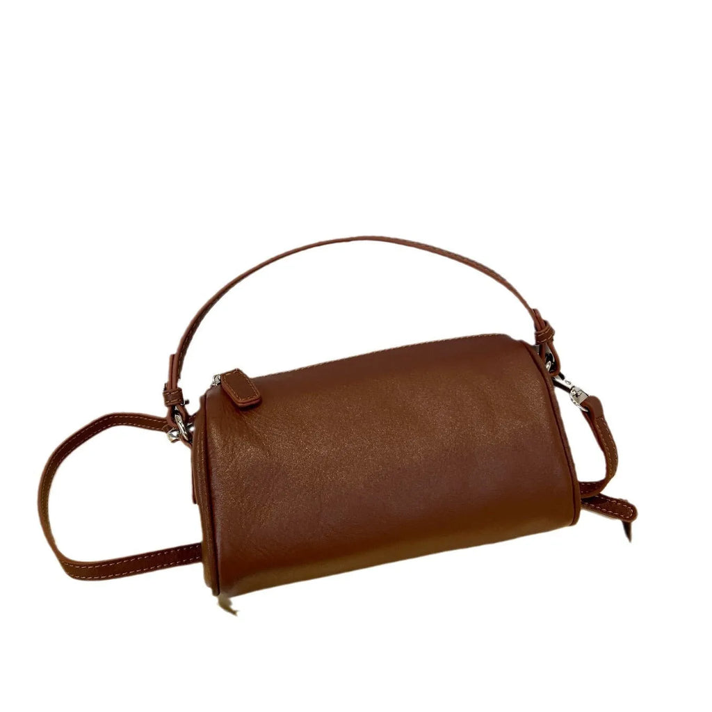 Vegetable-tanned leather crossbody phone bag with cylindrical shape and visible sewing thread detailing