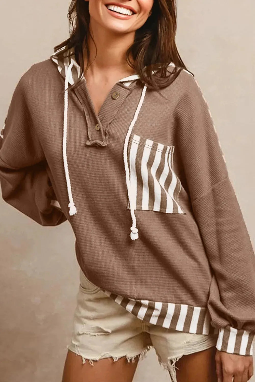 Straw yellow hoodie with waffle texture and striped patchwork design featuring drawstring hood and button neck closure