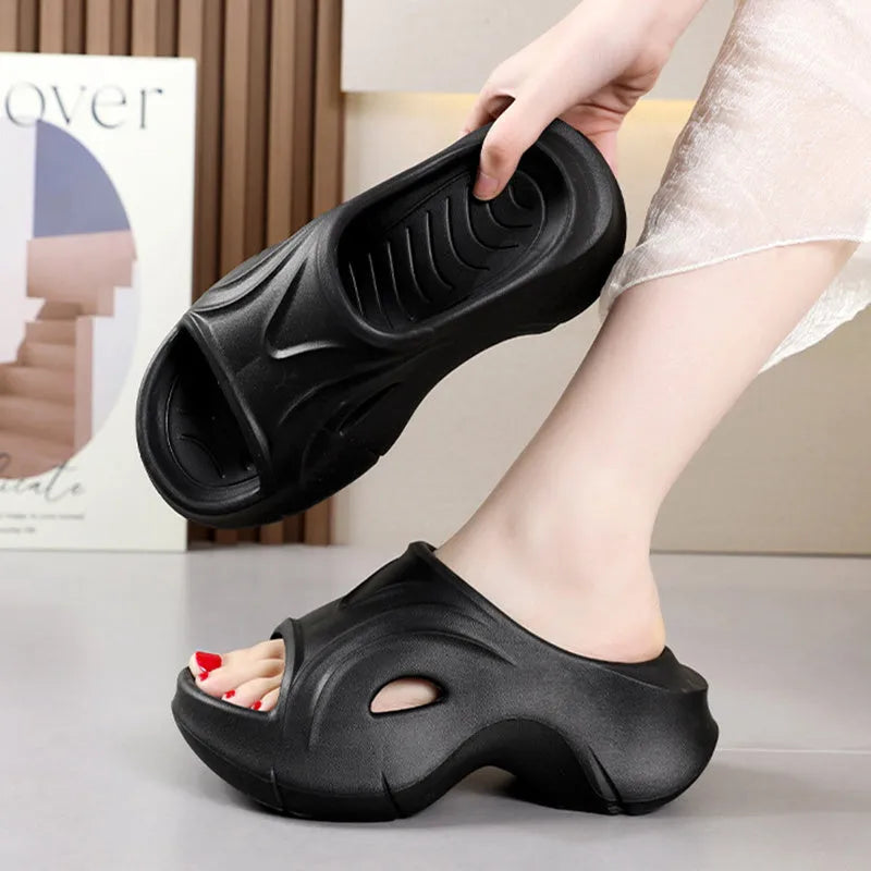 Women's white EVA slippers with a thick sole and round toe on a sandy beach.