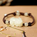 A Hetian jade bracelet with braided black and red rope in a Chinese style design.