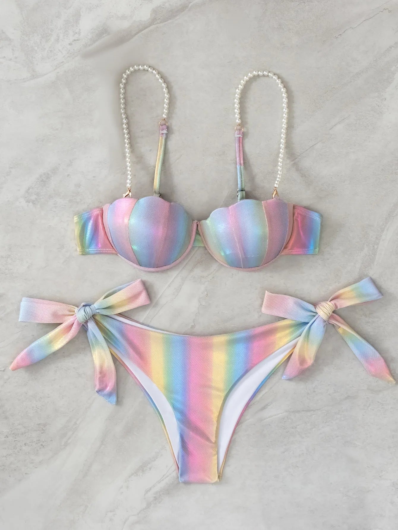 Women's shell rainbow patterned bikini swimsuit with a split tied front, on a mannequin.