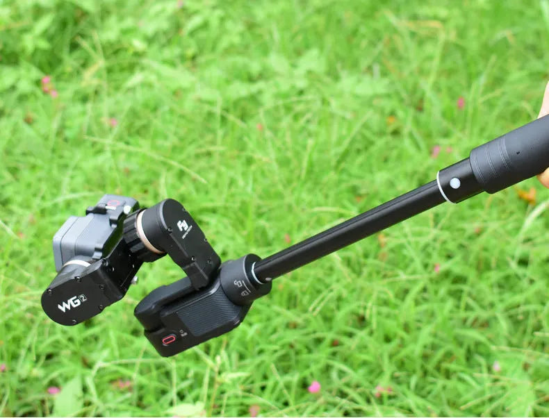 Black aluminium retractable selfie stick extended to full length with phone attached, showing included tripod stand and wireless remote.