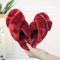 Women's black cross open-toe fur slippers with a patterned non-slip sole on a wooden floor