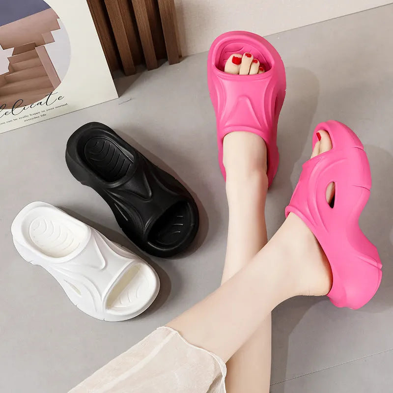 Women's white EVA slippers with a thick sole and round toe on a sandy beach.