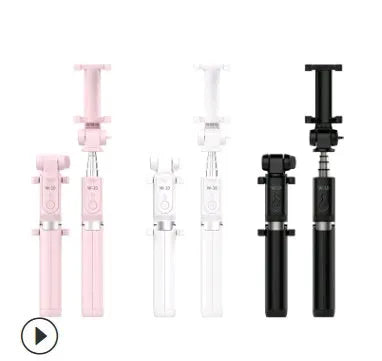 Black Bluetooth selfie stick with extended tripod legs and remote control next to a mobile phone.