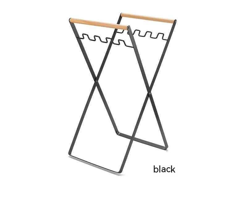 Black folding iron trash rack with wooden handles holding a bin bag outdoors