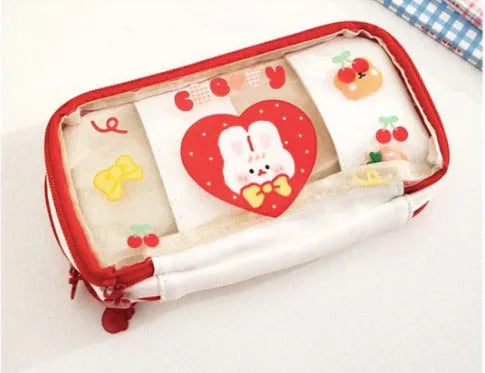 Transparent pink heart-shaped pen case with a cartoon cake and rabbit design, shown open.