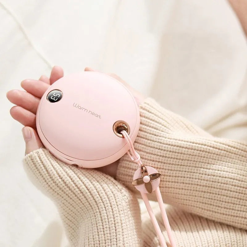 Green hand warmer power bank with digital display showing battery percentage, next to charging cable