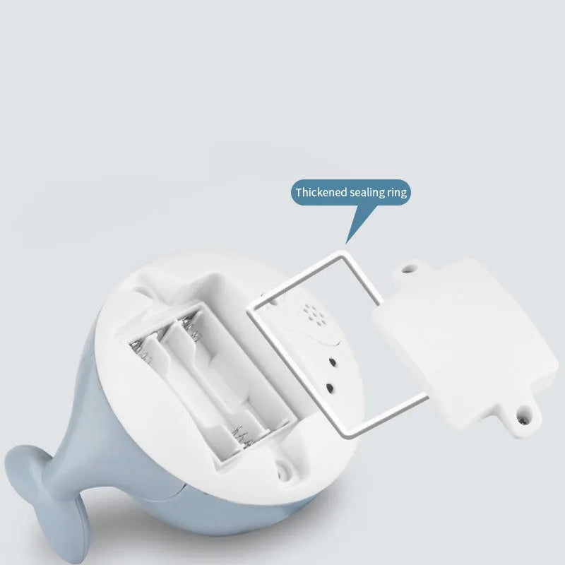 Whale-shaped electric bath toy spraying water with flashing lights, on a blue base.