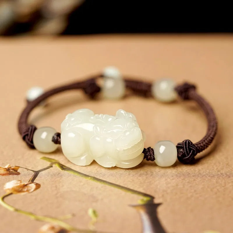 A Hetian jade bracelet with braided black and red rope in a Chinese style design.