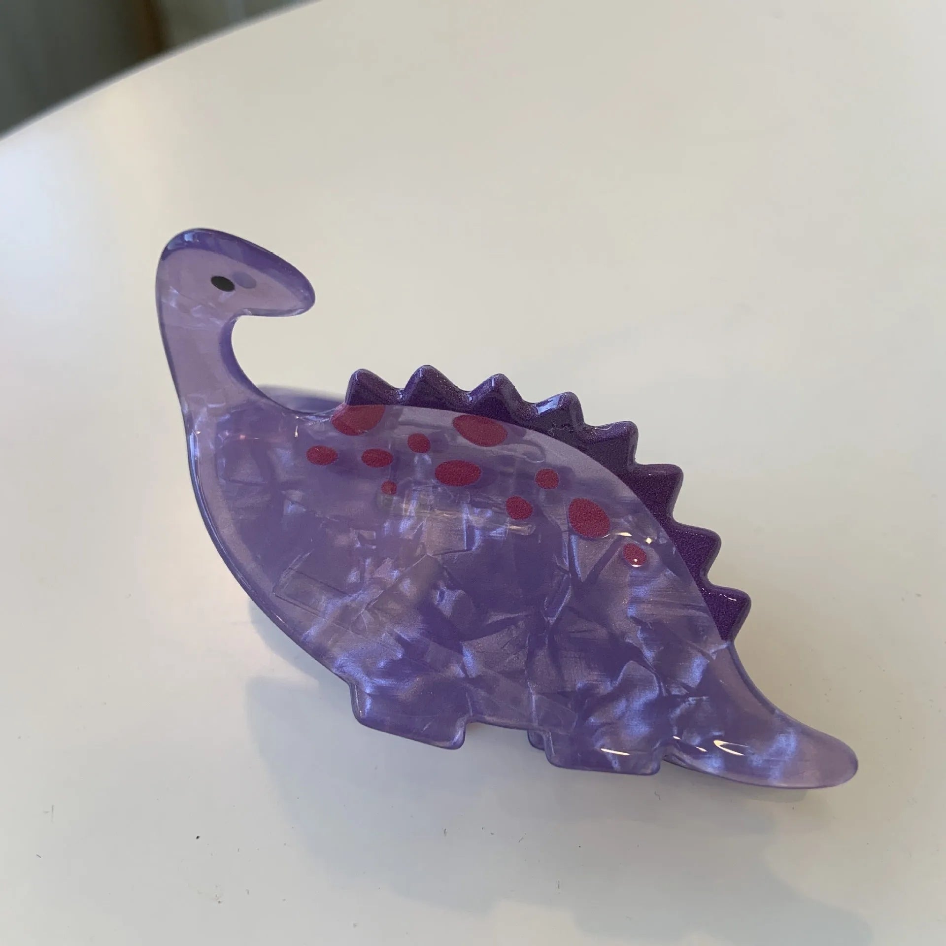 Acrylic dinosaur jaw grip hair clip showing six colour variations with prehistoric creature designs