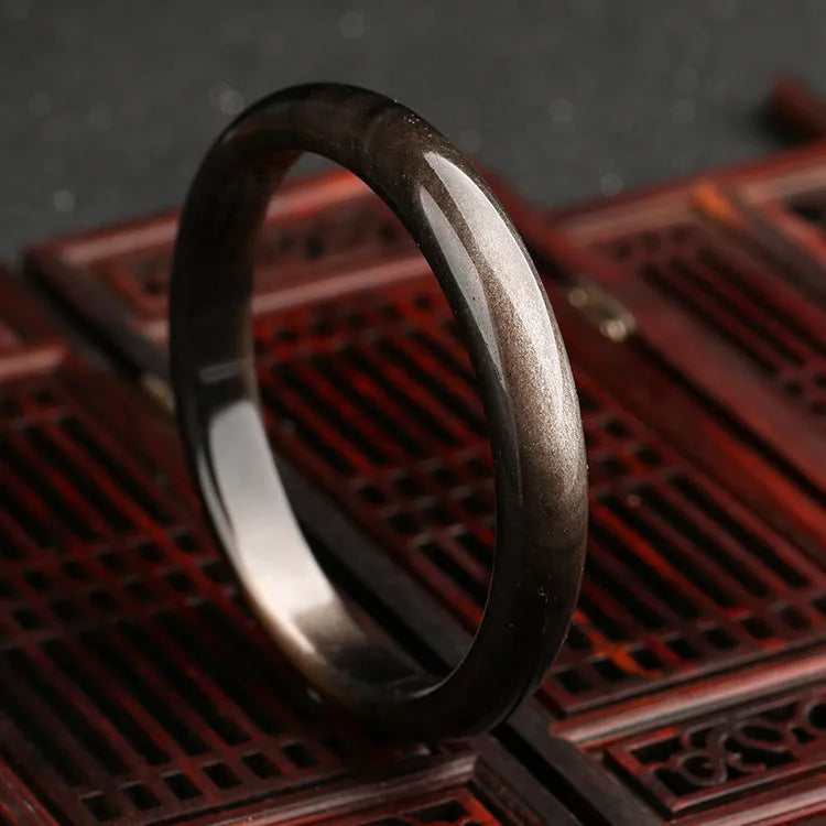 Natural silver stone cat's eye bracelet in obsidian style with ethnic geometric design on wrist.