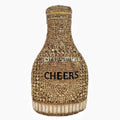 Gold hard-shell champagne bottle shaped evening clutch with rhinestones on a table.