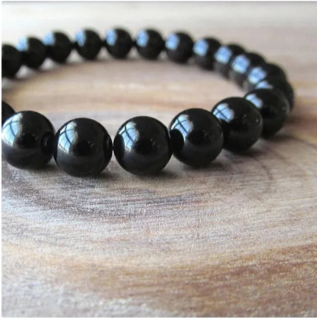 Women's geometric black agate bracelet with 8mm beads on a black elastic cord.