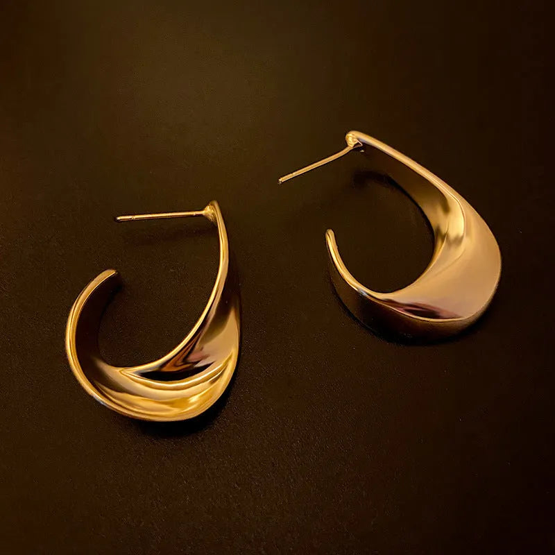 A pair of round, twisted geometric metal earrings with a gold electroplated finish.