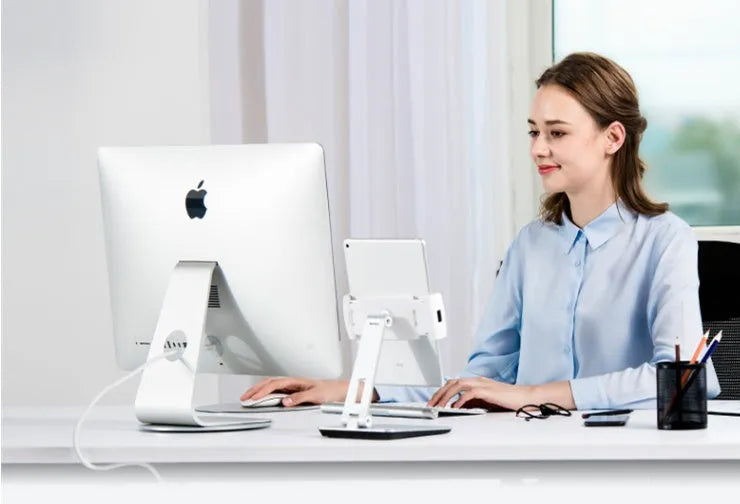 Folding aluminium phone and tablet stand on a desk, shown in silver colour with 360-degree rotation.