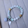 Natural green jade bracelet with a geometric pendant charm on a wrist.
