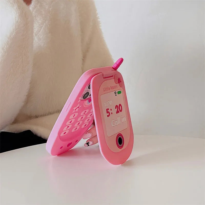 Pink silicone flip phone-shaped iPhone case with a built-in mirror and cute cartoon design.