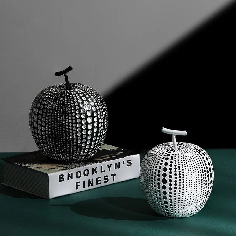 Resin decorative sculptures of apples and pears in black, white, orange and blue colours.