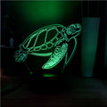 3D acrylic turtle-shaped LED night light with colour-changing modes on a table.