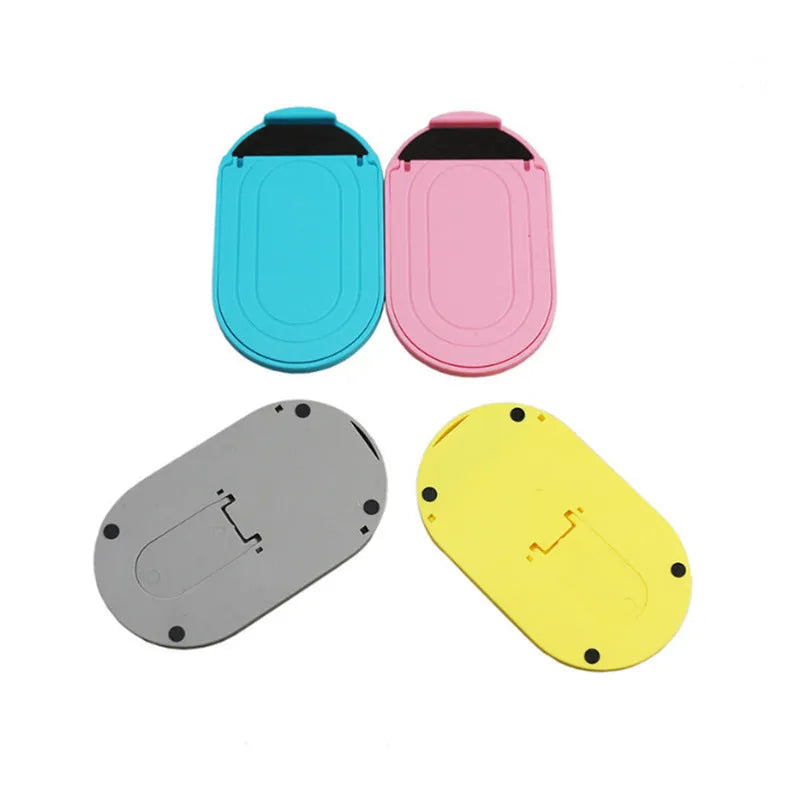 Plastic mobile phone stand with lazy bracket design in six colour options on a table.
