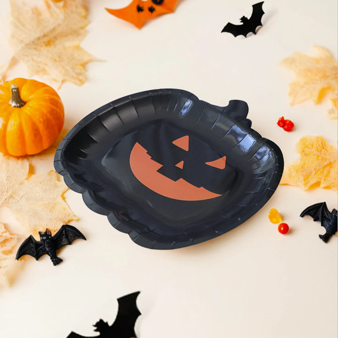 Black pumpkin-shaped disposable paper plates in 9-inch size for Halloween parties