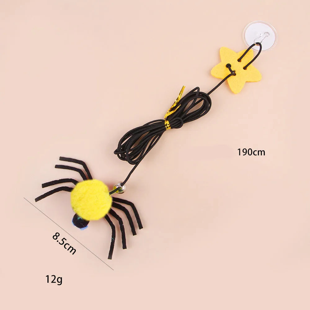 Red door hanging cat toy with elastic rope, feather, bell, and spider attachment on a white door.
