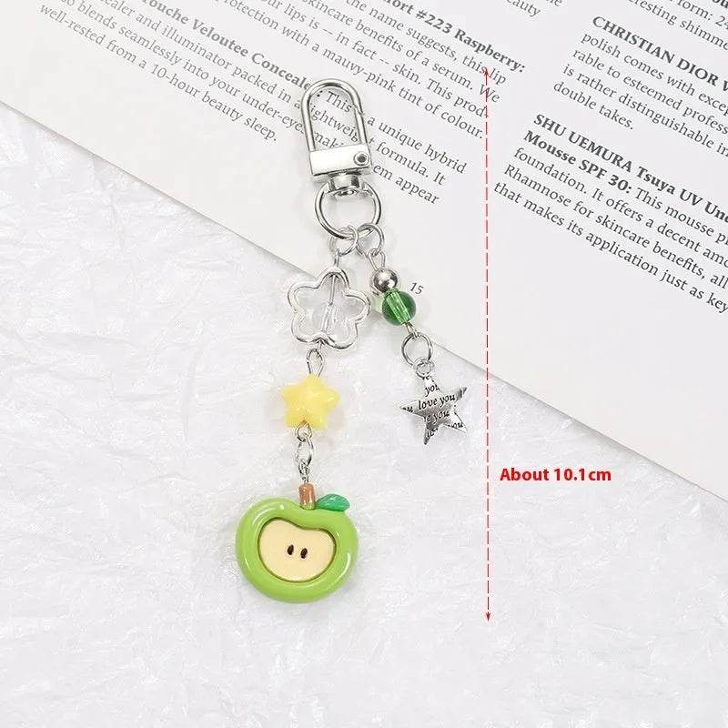 Plastic resin fruit pattern phone charm keychain pendant with apple and strawberry designs on a white rope.