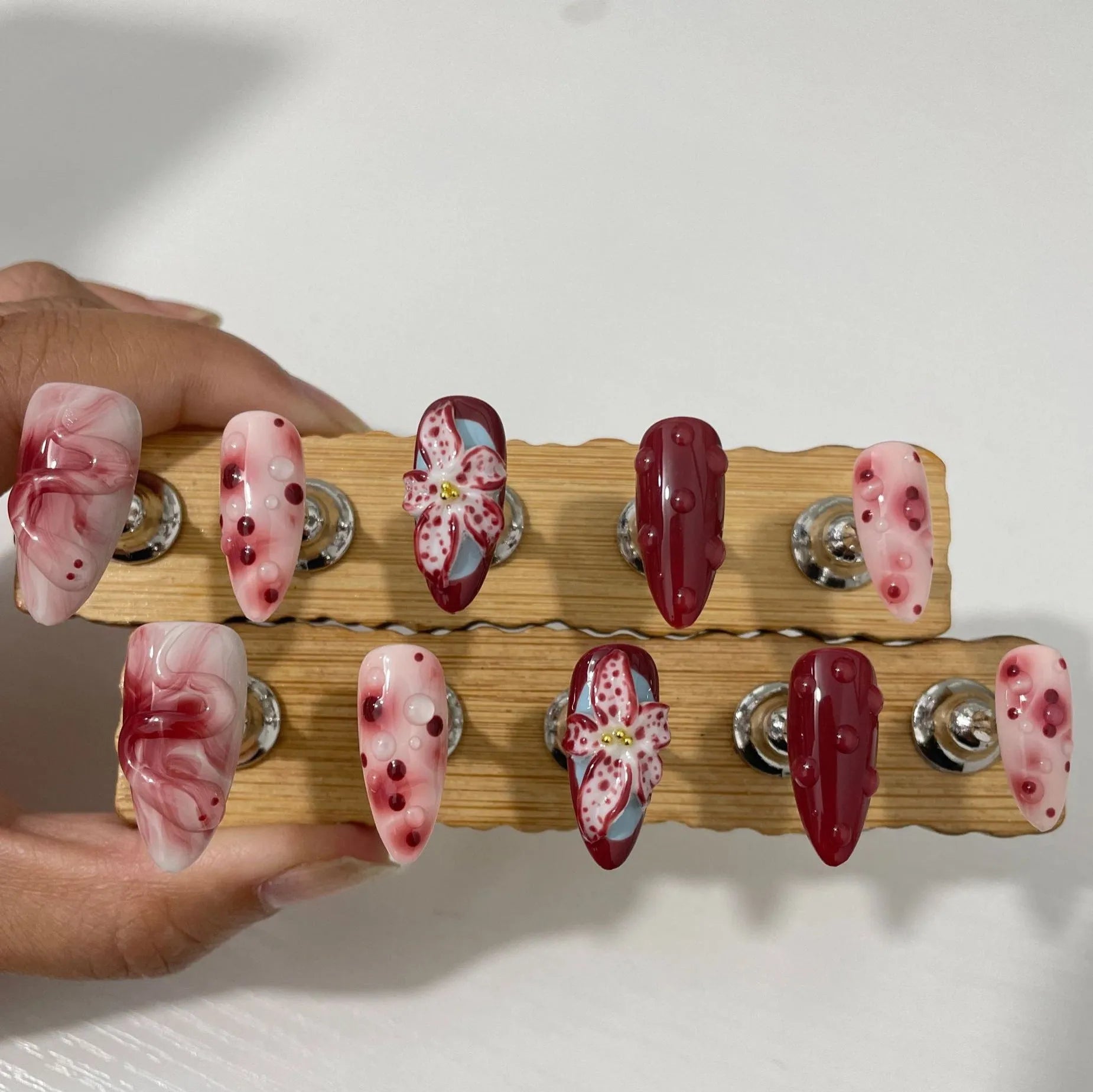 False nails set with three-dimensional hand-painted rose, tulip, shell, bow, and leopard print designs in almond colour