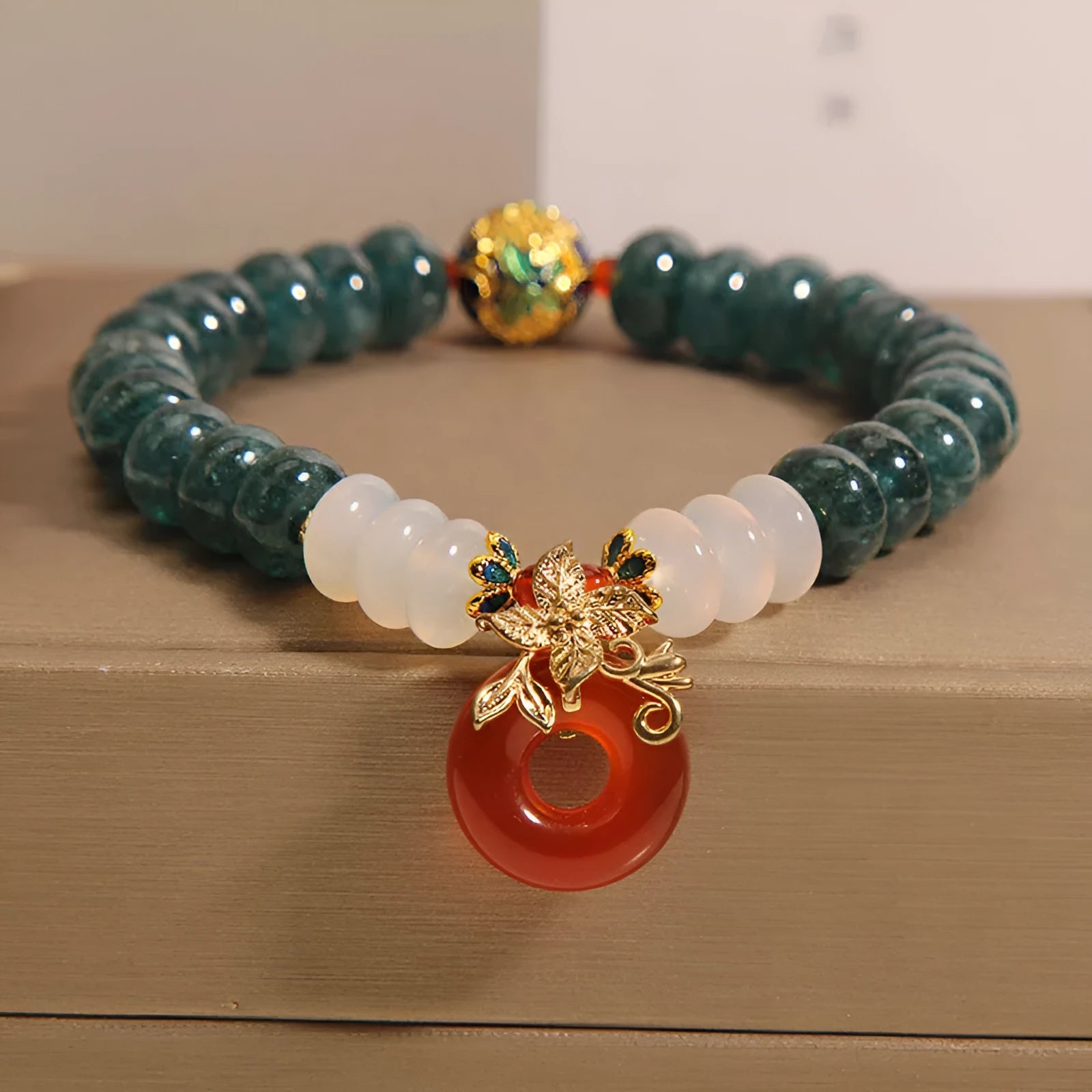 Blue water jade bead bracelet with red agate peace buckle closure and rhinestone details