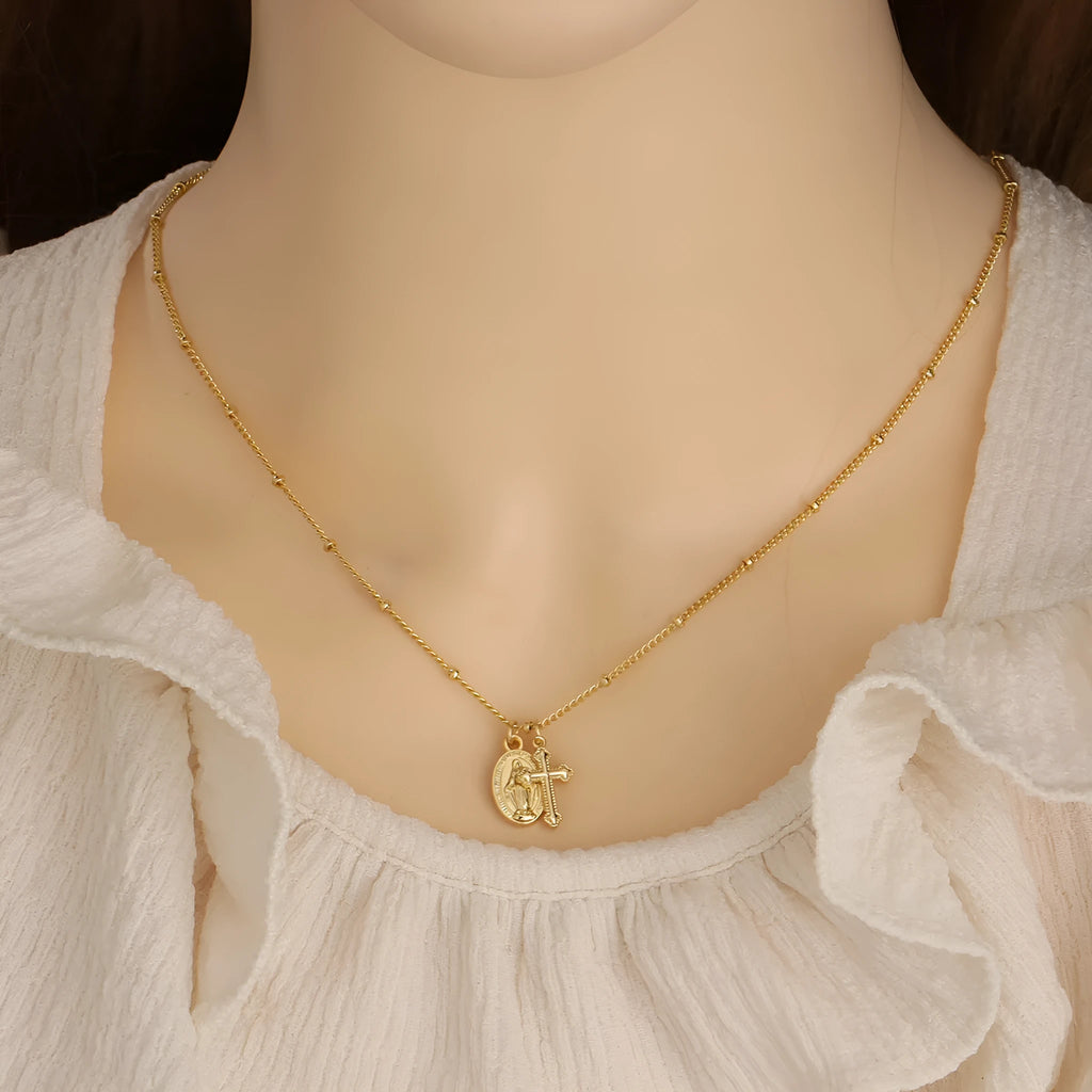 Geometric shaped gold tone pendant necklace with Cross and Virgin Mary ornament.