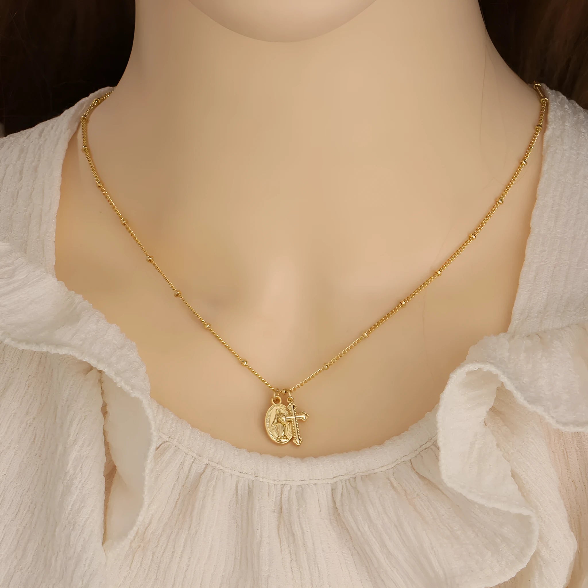 Geometric shaped gold tone pendant necklace with Cross and Virgin Mary ornament.
