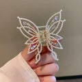 Elegant butterfly-shaped alloy hair clip for women, shown in rhinestone and pearl style options.