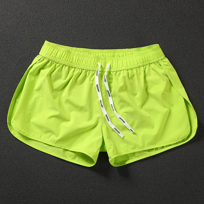 Men's loose orange beach shorts with elastic waistband on a sandy shore