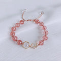 Handcrafted strawberry quartz crystal bracelet with peach blossom design on wrist