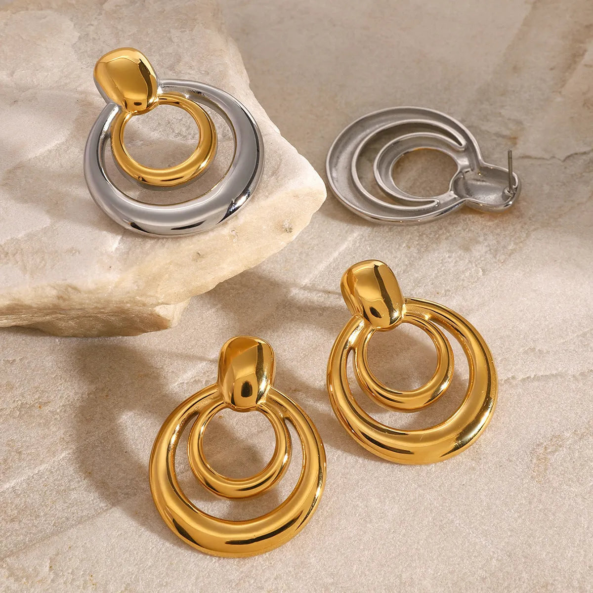 Round gold-coloured geometric hollow stud earrings on a white background.