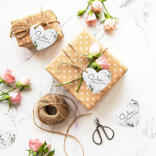 Set of 50 flower heart-shaped paper gift tags in two vintage designs on a table.