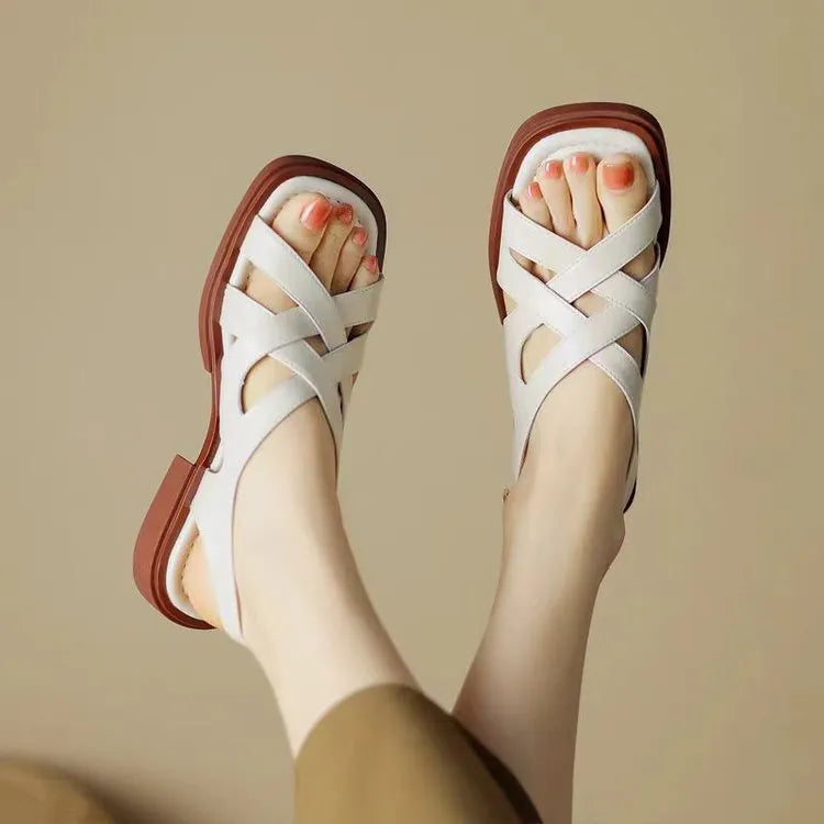 Women's black patent leather low heel sandals with square toe and cross ankle strap.