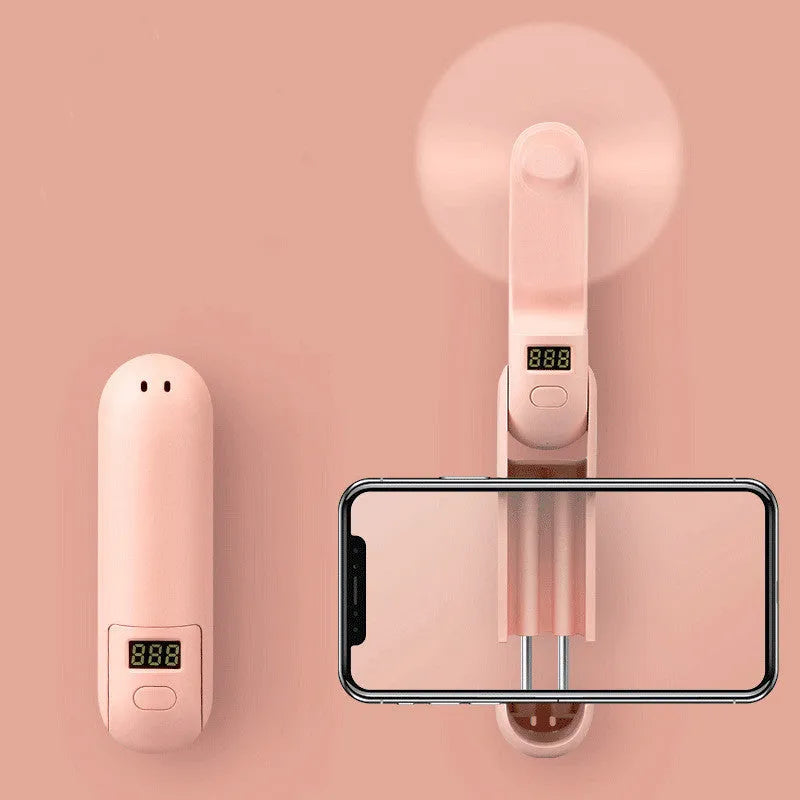 Folded and unfolded views of a green portable mini USB rechargeable fan on a table.