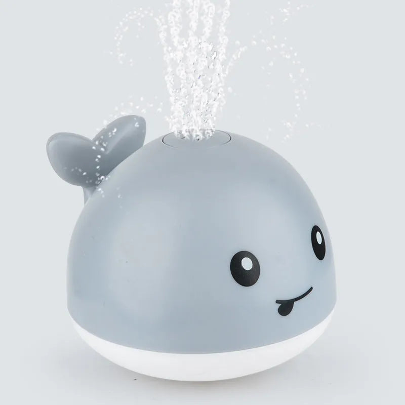 Whale-shaped electric bath toy spraying water with flashing lights, on a blue base.