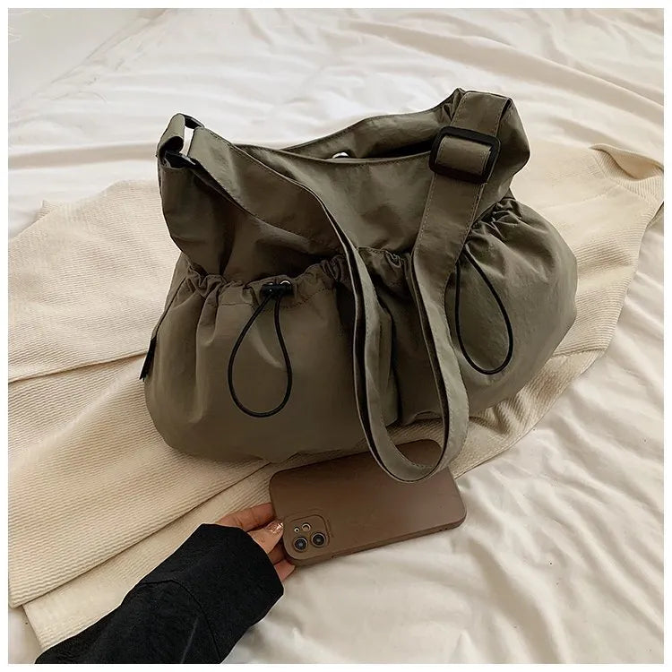 Ultra-light pleated foldable crossbody bag in soft polyester fabric, shown in green with split pockets.