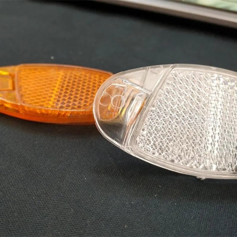 White and yellow plastic bicycle spoke reflectors measuring 7.2cm by 3.5cm for safety visibility