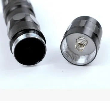 Small black aluminium LED mini flashlight shown next to a AA battery for scale.